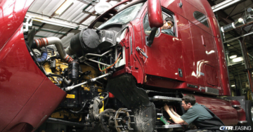 Two diesel mechanics performing routine maintenance on a truck